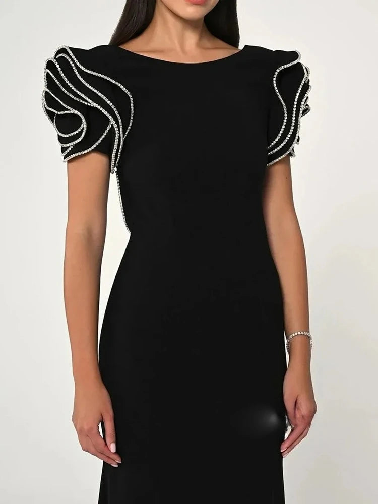 Close-up of the black maxi dress highlighting the sculpted ruffle sleeve detailing and smooth fabric finish.