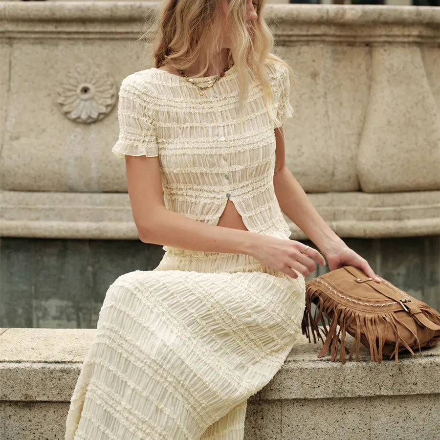 Woman wearing ruched two-piece skirt set seated outdoors with neutral accessories