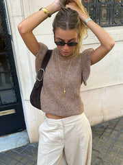 Close view highlighting the ruffled shoulder detailing and smooth knit finish around the neckline.