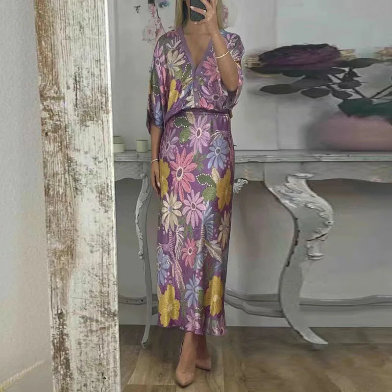 Person wearing a colourful satin floral print on a two-piece co-ord set, taking a mirror selfie in a room with a table and decorative items.