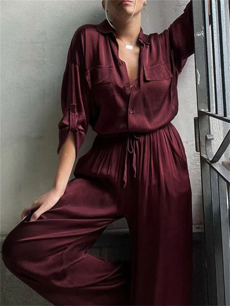 Person wearing a burgundy jumpsuit with a Close-up of a burgundy satin shirt and an elasticated waistband detail.
