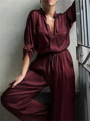 Person wearing a burgundy jumpsuit with a Close-up of a burgundy satin shirt and an elasticated waistband detail.