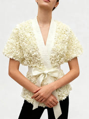 Cream V-neck tunic featuring sculptural flower detailing