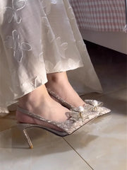 A close-up of the sequin and pearl bow detail on the shoe.