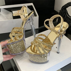 Gold glitter high-heeled shoes on a white surface with a blurred background