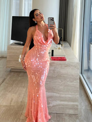 Woman in a sequin halter maxi dress, styled for a glamorous summer party, taking a mirror selfie in a modern room.