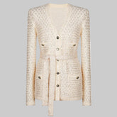 Front view of a beige textured knit coat with a waist tie and button details, presented cleanly against a studio background.