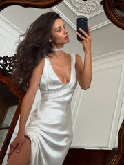 Woman in a slim sheath dress in satin with delicate lace detail for weddings taking a mirror selfie in an elegant room.