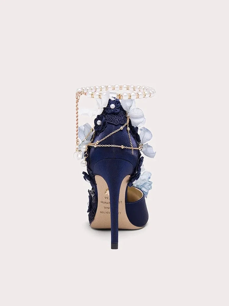 Navy blue high-heeled shoe with floral embellishments on a light gray background