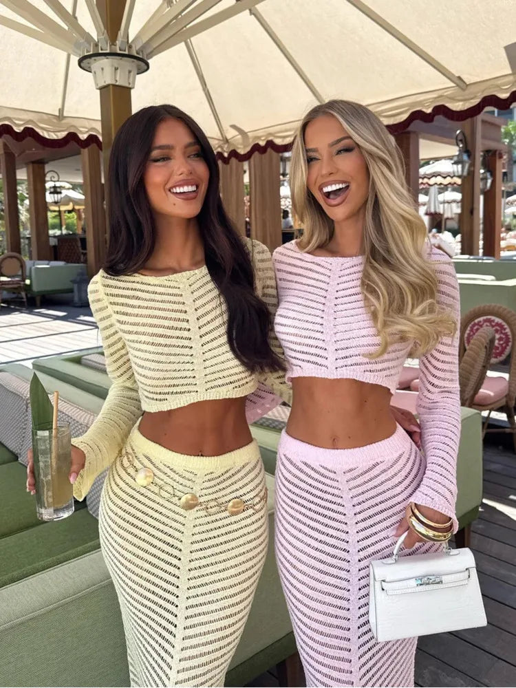Two women wearing sheer knit co-ord sets with long skirts in an outdoor café