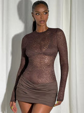 Studio front view of a brown sheer lace mini dress with long sleeves, a high round neckline, and a body-skimming ruched finish.