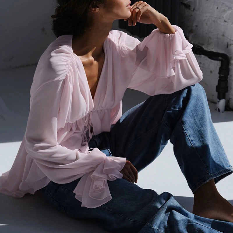 Side profile of a woman wearing a butterfly sleeve blouse showing light drape and fit, sitting on a surface.