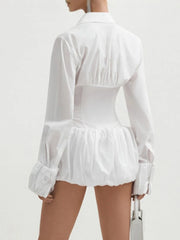 Side back view of a model wearing a long-sleeve shirt dress in white with pleated waist detail on a plain background.