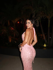 Woman in a glittering orange maxi dress for vacation evenings or birthdays, standing outdoors at night with palm trees in the background