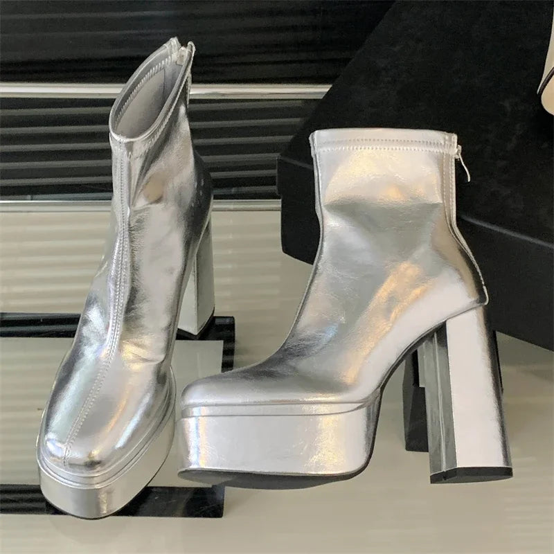 Silver platform ankle boots on a black stand with a blurred background
