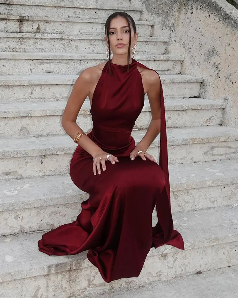 Woman in a burgundy evening gown sitting on stone steps.