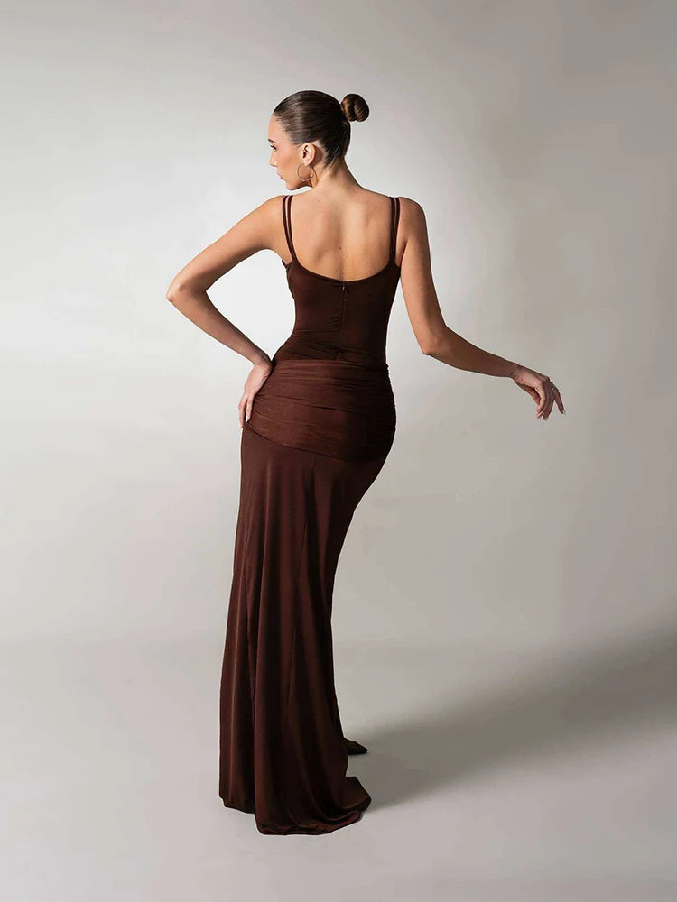 A sleeveless draped long dress styled with heels and a clutch.