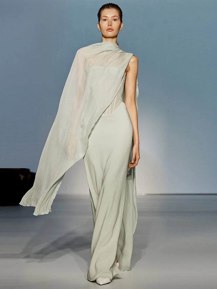 Model wearing a sleeveless mesh scarf, ankle-length gown in mint for evening parties, with a flowing fabric on a plain background