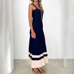 Woman wearing a sleeveless metal button maxi dress in navy and white for summer events against a white background
