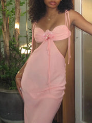 A woman wearing a blush formal dress with a slim silhouette and an elegant neckline with floral details in an outdoor setting