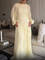 Soft yellow pleated maxi dress styled for elegant living room setting