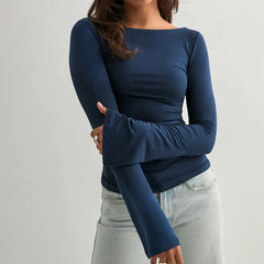 A woman modeling a solid boat neck flare long sleeve top.