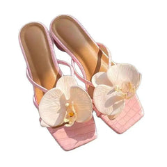 Pink sandals with white floral decorations on a white background