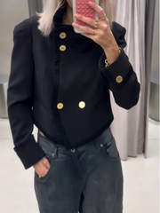 Mirror selfie showing a black cropped jacket with a stand collar and polished gold-tone buttons, styled with dark denim in a fitting room.