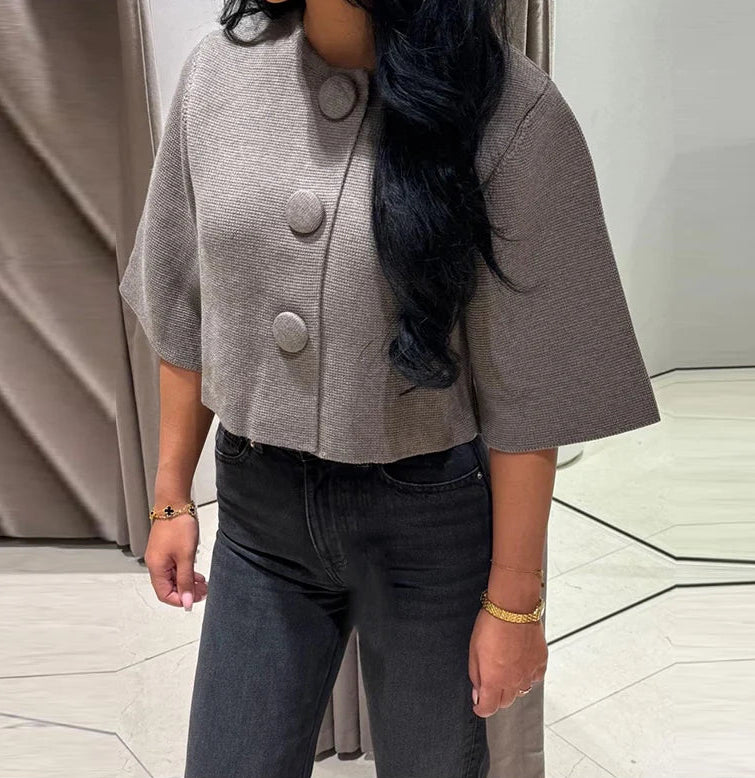 Close view highlighting the textured gray knit and bold round buttons on the cropped cardigan, showing the clean front finish.