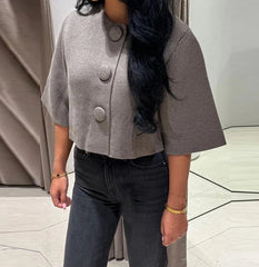 Close view highlighting the textured gray knit and bold round buttons on the cropped cardigan, showing the clean front finish.