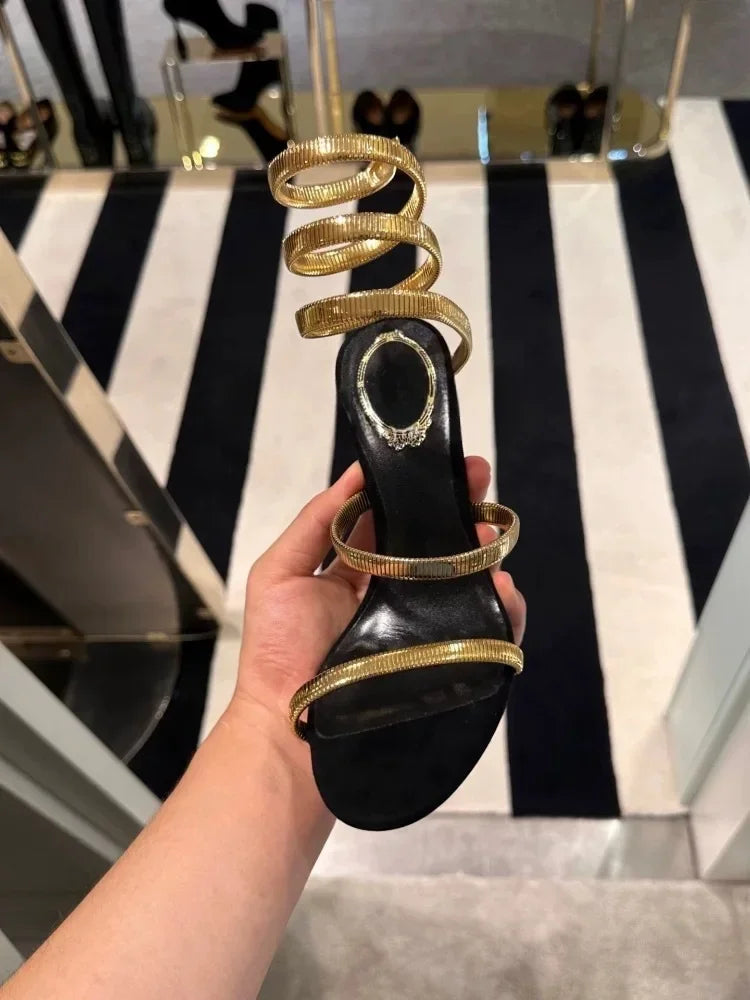 Statement gold stiletto ankle sandals with unique sculptural strap