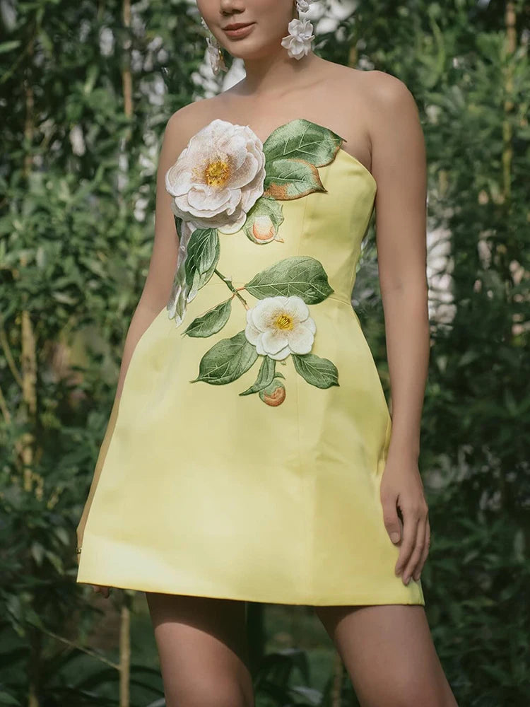 A woman wearing a strapless yellow mini dress with a zipper closure in a natural setting.
