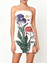 Model wearing a strapless white mini dress with bold floral beadwork