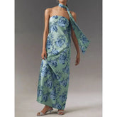 Woman wearing a strapless floral satin dress styled for summer evenings with a matching scarf on a neutral background
