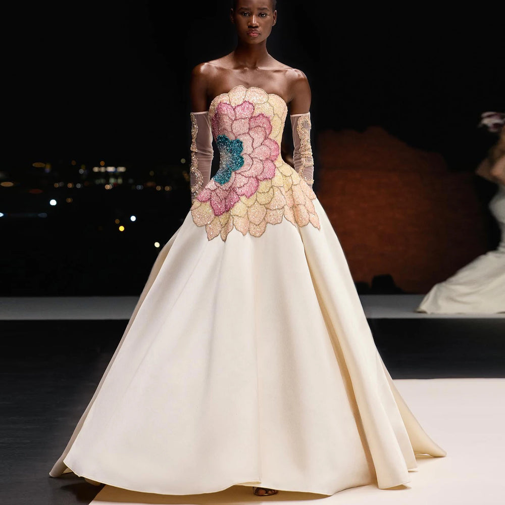 A woman wearing an elegant strapless satin evening gown with a pair of long gloves.