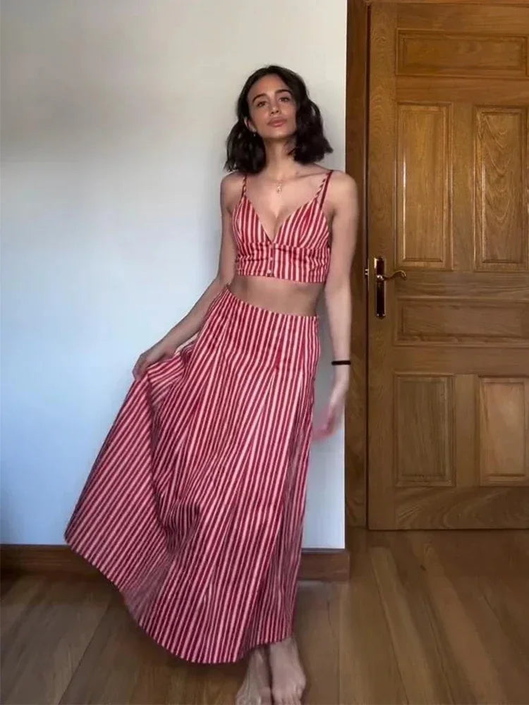 Woman wearing a red and white striped outfit standing in a room with wooden flooring and a wooden door.