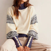 Model seated wearing a crew-neck knit sweater with striped statement sleeves and ribbed trims styled with tailored trousers.