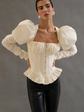 Close-up showing the structured seam detailing and button-front look on an ivory corset-style blouse, with gathered fabric at the neckline.