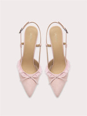 A pair of pink suede sandals with a lace bow.