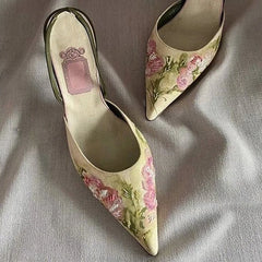 Pair of floral high-heeled shoes on a textured fabric background