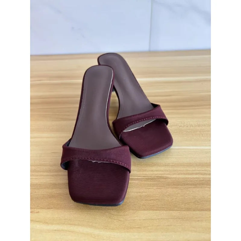 Elegant maroon mule sandals on wooden surface