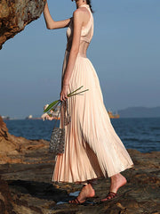 A woman in a coastal formal dress, perfect for sunset weddings, standing on rocks by the ocean.