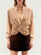 Model wearing a draped blouse with a twisted front detail.