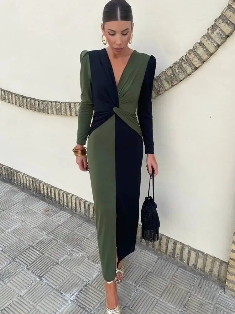 Editorial street styling of a two-tone deep V-neck ruched maxi dress with long sleeves and ankle-length slit.
