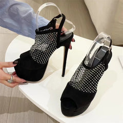 Black high-heeled shoes with rhinestone detailing on a white surface.