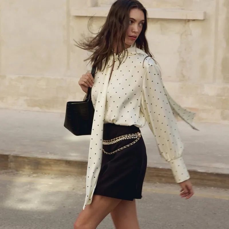 Polka dot blouse styled with a structured mini skirt and chain belt detail