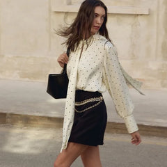 Polka dot blouse styled with a structured mini skirt and chain belt detail