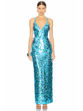 Model wearing a blue V-neck sequin maxi dress with thin straps, standing against a clean studio background.
