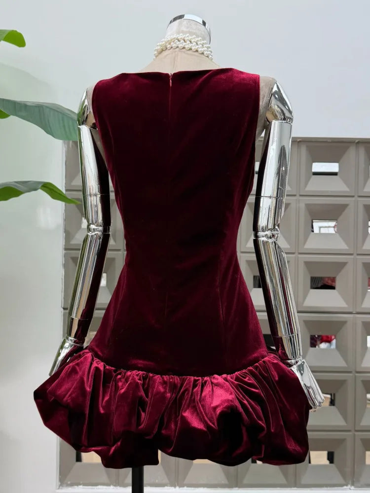 Back angle showing the fitted body and flared cloud hem silhouette of a velvet sleeveless mini dress on a mannequin.