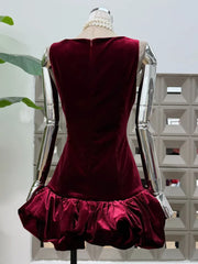 Back angle showing the fitted body and flared cloud hem silhouette of a velvet sleeveless mini dress on a mannequin.
